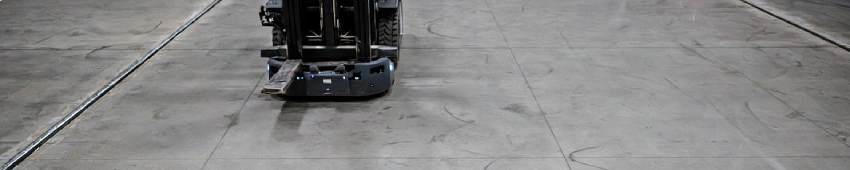 Localized concrete floor joint deviation in an automated warehouse, showing how small elevation discontinuities can disrupt robotic navigation and system stability.