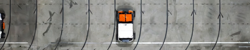 Repeated AMR travel paths visible on a superflat concrete floor inside an automated warehouse.