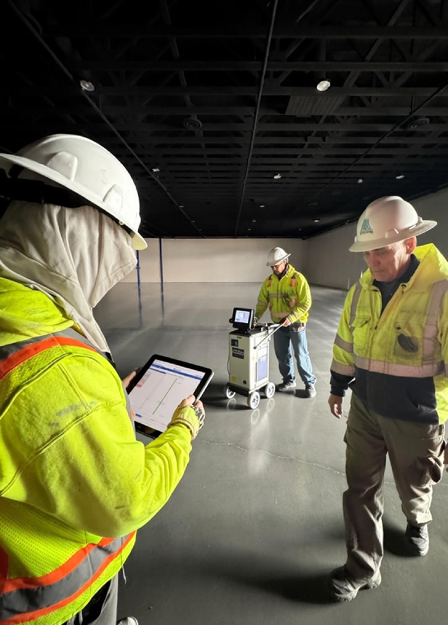 Industrial floor performance testing crew measuring concrete flatness using digital tools to verify FF/FL compliance in an automation-ready facility.
